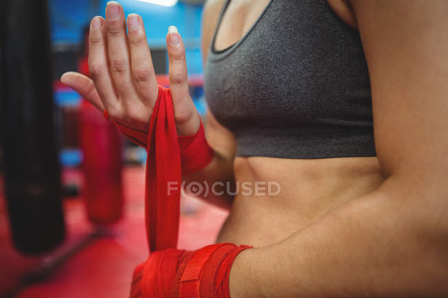 Mittelteil einer Boxerin mit rotem Riemen am Handgelenk im Fitnessstudio — Stockfoto
