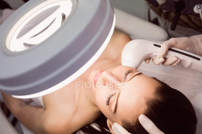 Doctor giving facial massage to patient through sonic lifting in clinic — Stock Photo