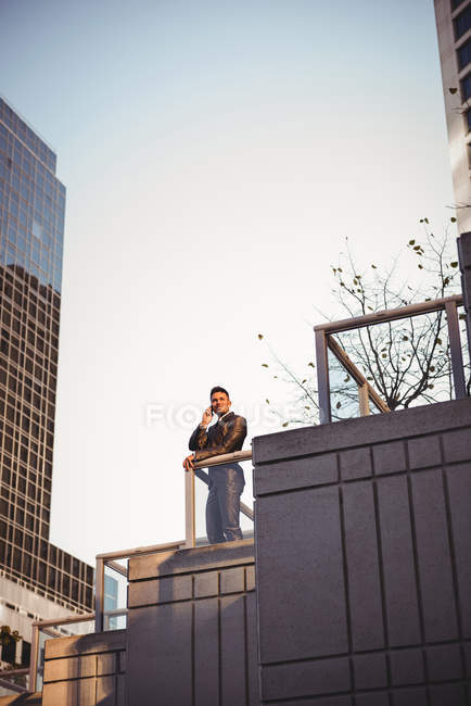 Homme d'affaires parlant sur un téléphone portable près d'un immeuble de bureaux — Photo de stock