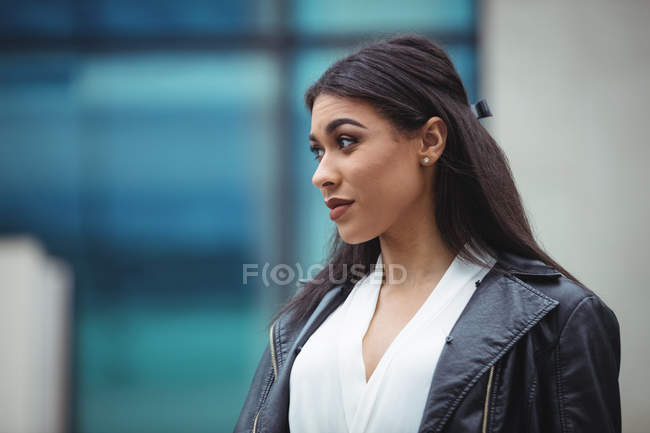 Вдумчивая женщина, стоящая возле офисного здания — стоковое фото