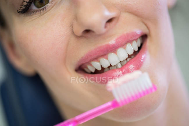 Dentist assisting young patient while brush teeth in dental clinic — Stock Photo