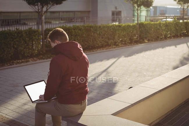 Чоловік виконавчий використовує ноутбук перед офісною будівлею — стокове фото