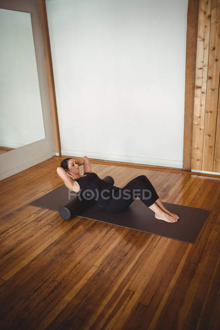 Healthy woman exercising with foam roll in fitness studio — Stock Photo