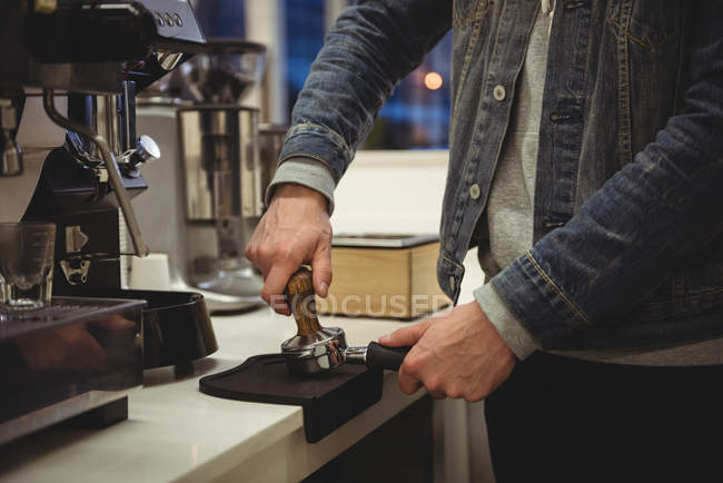 Man pressing coffee with tamper in portafilter in coffee shop — Stock Photo