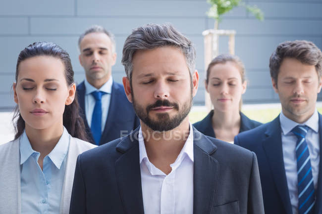 Groupe de gens d'affaires les yeux fermés devant un immeuble de bureaux — Photo de stock