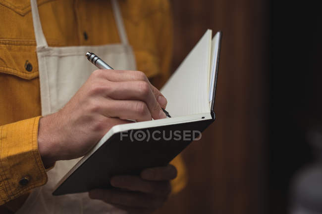 Close-up de homem escrevendo em livro de notas em casa cervejaria — Fotografia de Stock