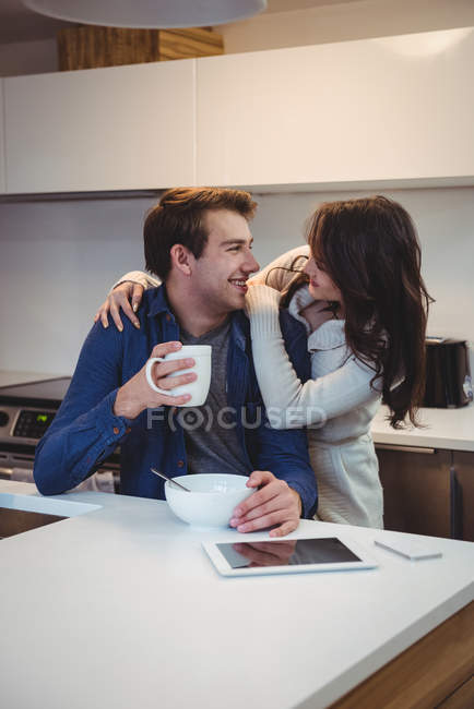 Casal interagindo uns com os outros enquanto toma café da manhã na cozinha em casa — Fotografia de Stock