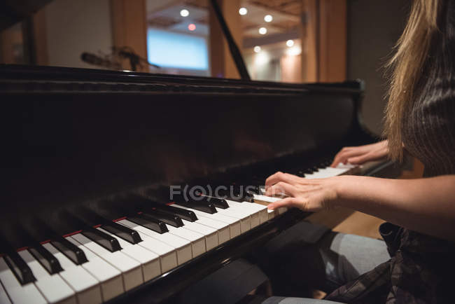 Metà sezione di donna che suona un pianoforte in studio musicale — Foto stock