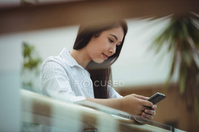 Mujer de negocios usando teléfono móvil en el balcón de la oficina - foto de stock