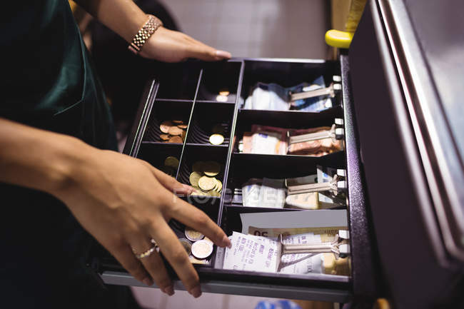 Sección media del personal femenino de pie en el mostrador de efectivo en el supermercado - foto de stock