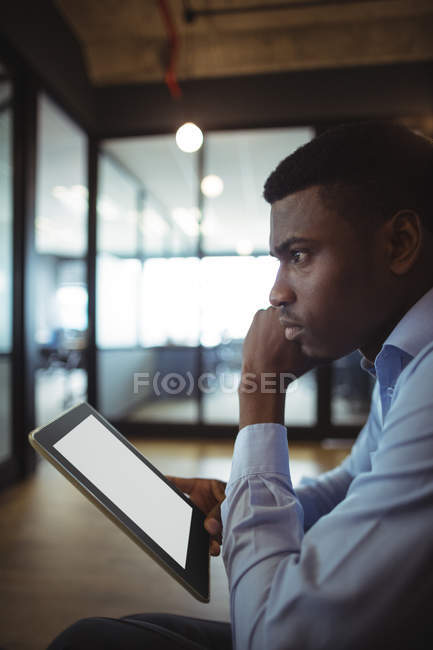 Pensativo empresario sosteniendo tableta digital en la oficina - foto de stock