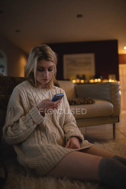 Mulher usando telefone celular enquanto está sentado em casa — Fotografia de Stock