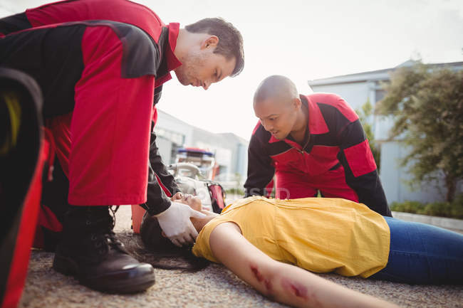 Парамедики осматривают раненую женщину на улице — стоковое фото