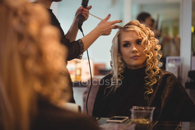 Female hairdresser styling clients hair in saloon — Stock Photo