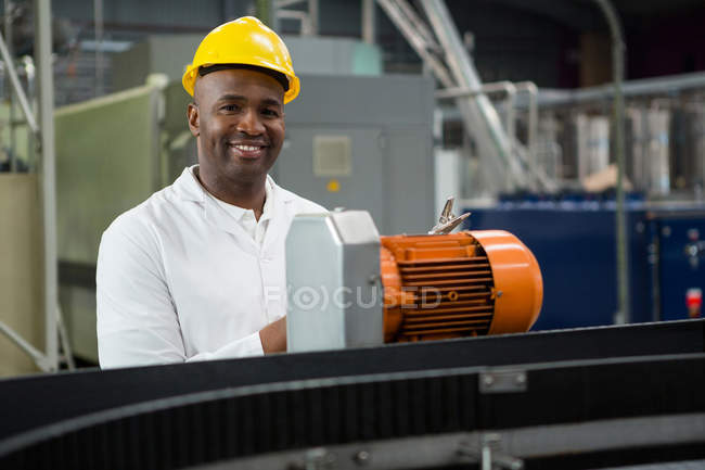 Retrato del ingeniero sonriente inspeccionando máquinas en la fábrica de zumos - foto de stock