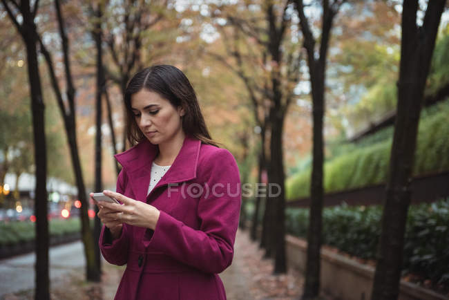 Beautiful businesswoman using phone standing on the pathway — Stock Photo
