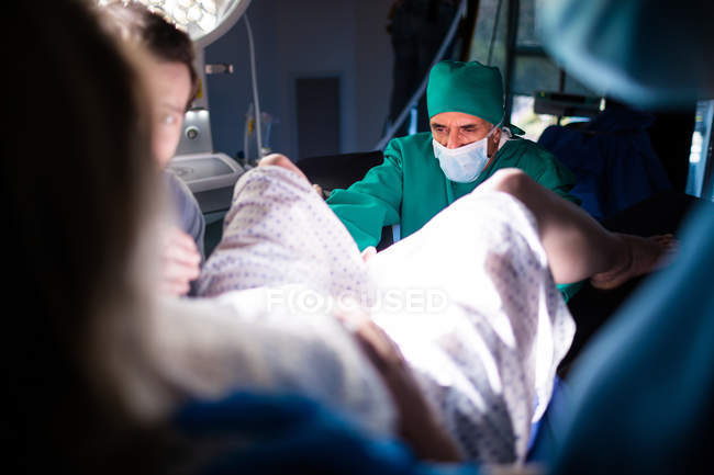 Доктор вивчає вагітну жінку під час доставки в операційну кімнату — стокове фото