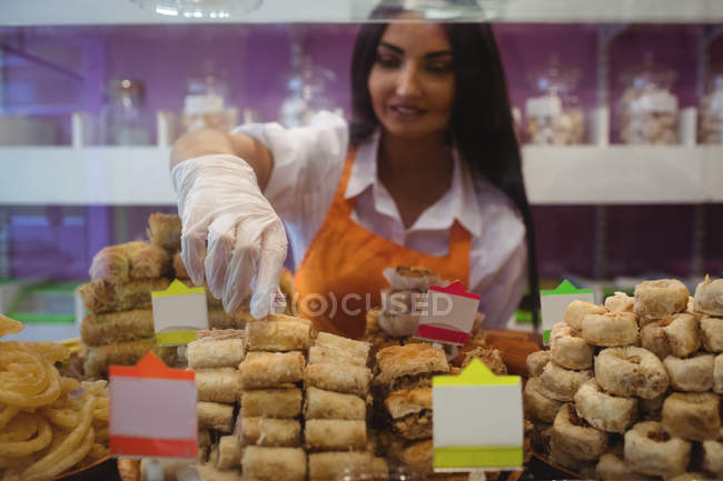 Female shopkeeper arranging turkish sweets at counter in shop — Stock Photo