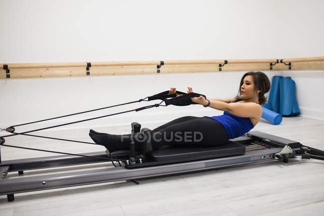 Mid adult woman exercising on reformer in gym — Stock Photo