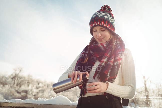 Schöne Frau im Winter trägt im Skiurlaub einschenkendes Getränk im Becher — Stockfoto