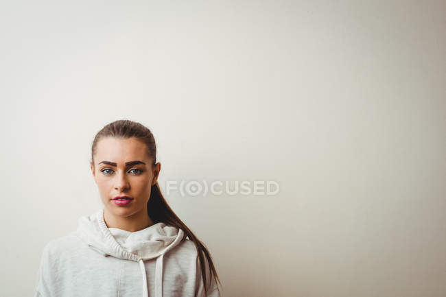 Portrait of young woman against white wall — Stock Photo