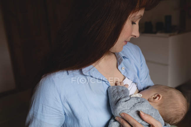 Крупный план матери грудного вскармливания ребенка в спальне дома — стоковое фото