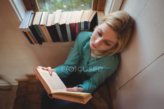 Hermosa mujer leyendo libro en casa - foto de stock