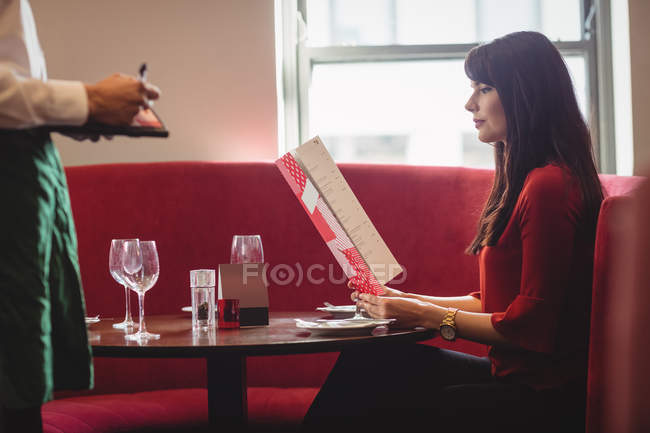 Официант принимает заказ от женщины в ресторане — стоковое фото