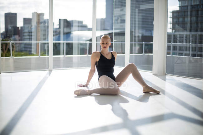 Балерина отдыхает на полу в интерьере балетной студии — стоковое фото