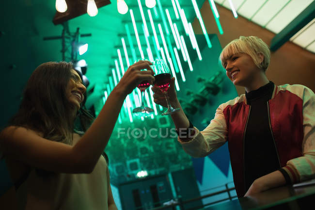 Amigos sonrientes brindando copas de vino en el bar - foto de stock