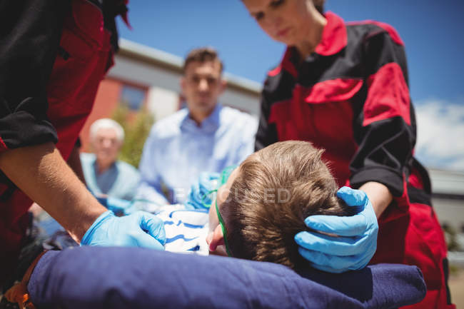 Парамедики осматривают раненого мальчика на улице — стоковое фото