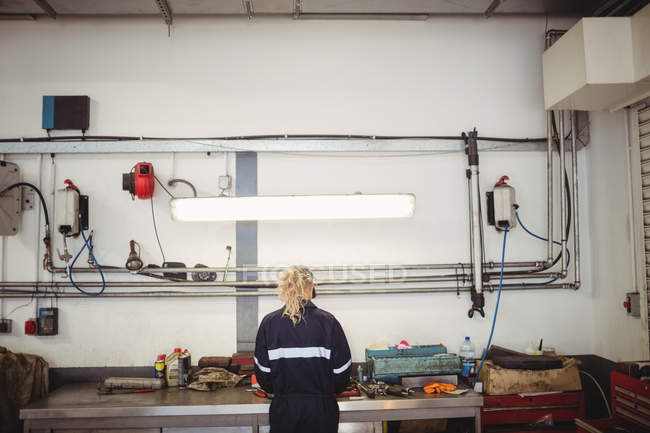 Visão traseira do mecânico feminino que trabalha na garagem de reparação — Fotografia de Stock