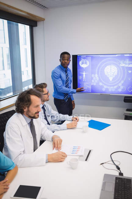 Doctor giving presentation to team of interim doctors at conference room — Stock Photo