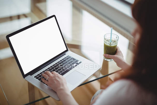 Вагітна жінка використовує ноутбук, маючи сік вдома — стокове фото