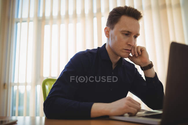 Executivo masculino usando laptop no escritório — Fotografia de Stock