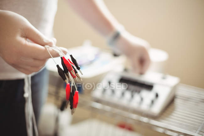Close-up of physiotherapist holding cables of electro dry needling unit — Stock Photo