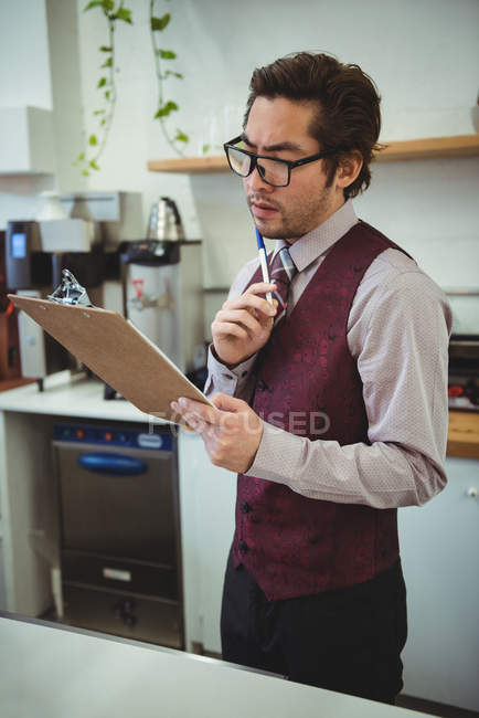 Вдумчивый человек смотрит на планшет в кофейне — стоковое фото