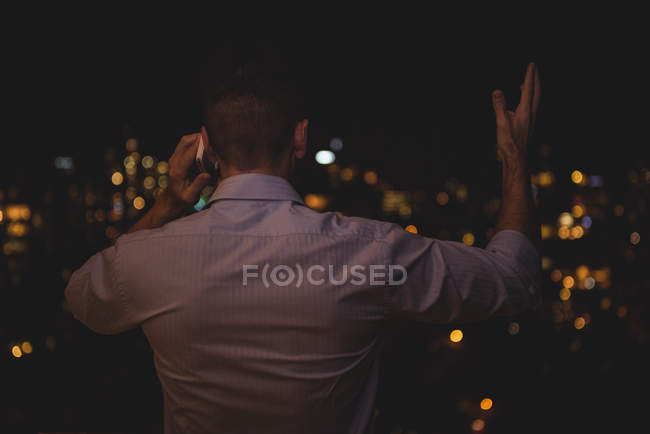 Rear view of man talking on mobile phone at night — Stock Photo