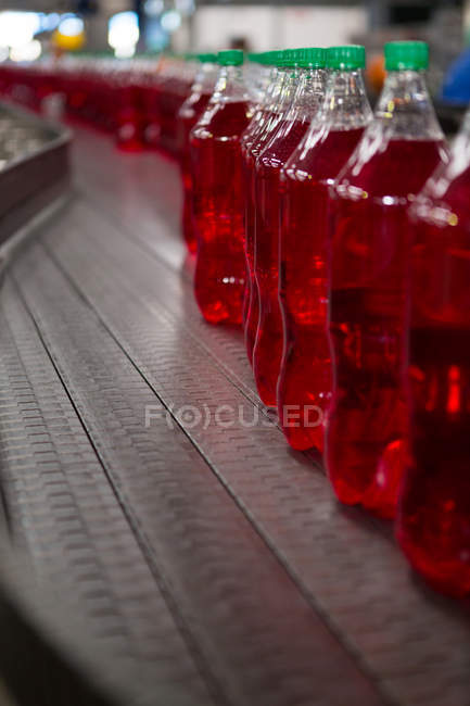 Close up de garrafas de suco vermelho na linha de produção na fábrica — Fotografia de Stock