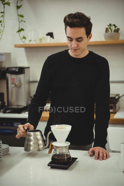Man in cafe pouring hot water in the pot through the filter — Stock Photo