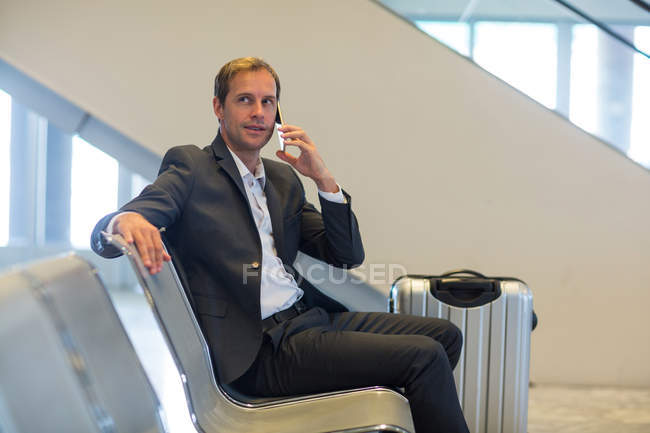 Бізнесмен розмовляє по мобільному телефону в зоні очікування в терміналі аеропорту — стокове фото