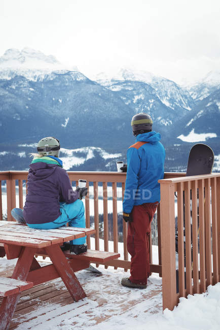 Vue arrière du couple en balustrade contre la montagne enneigée pendant l'hiver — Photo de stock