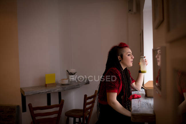 Belle femme regardant par la fenêtre tout en buvant une boisson santé au café — Photo de stock
