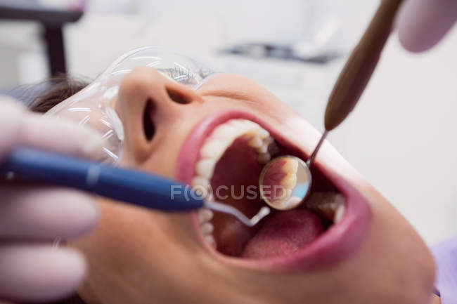Dentiste examinant patiente avec des outils à la clinique dentaire — Photo de stock
