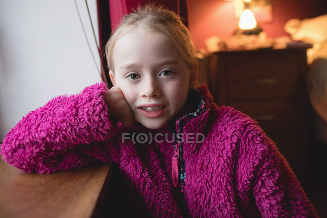 Portrait of cute elementary age girl in pink sweater in bedroom at home — Stock Photo