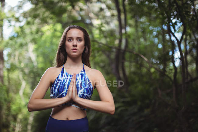 Mujer realizando yoga en el bosque en un día soleado - foto de stock