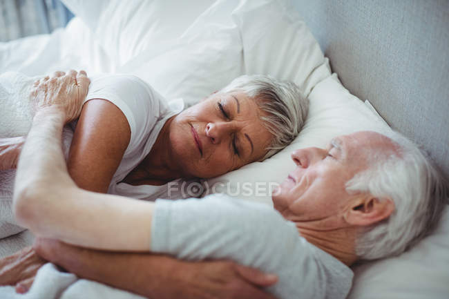 Seniorenpaar schläft auf Bett im Schlafzimmer — Stockfoto