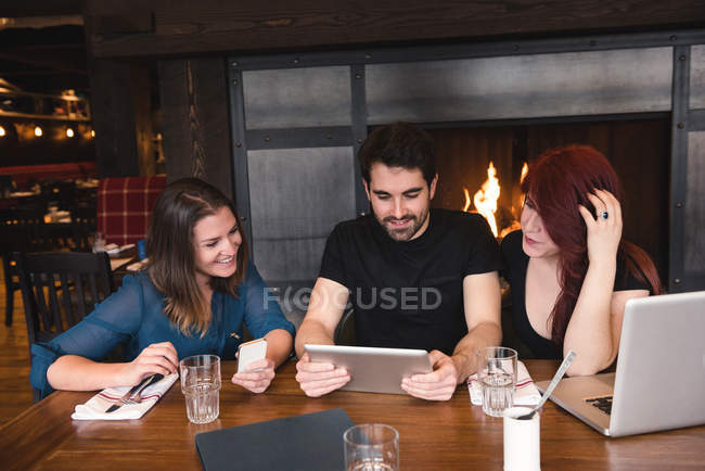 Друзья сидят за столом и используют цифровой планшет в баре — стоковое фото