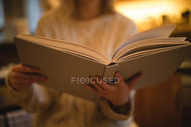 Mid-section of woman reading book in kitchen at home — Stock Photo