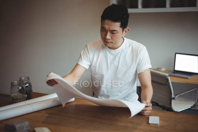 Business executive looking at blueprint in office — Stock Photo